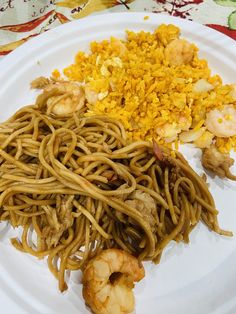 a white plate topped with noodles and shrimp next to other foods on a floral table cloth