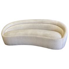 an oval shaped couch with three pillows on it's sides and one arm extended to the side