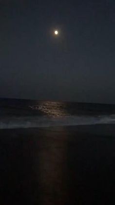 the moon is shining over the ocean at night