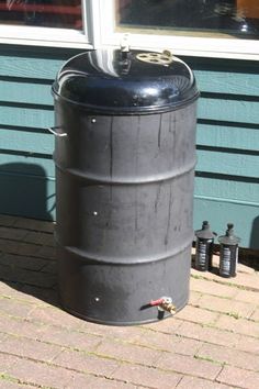 a large metal barrel sitting on top of a wooden deck next to a building with blue siding