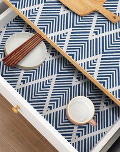 two chopsticks and plates on top of a blue patterned tablecloth with geometric design