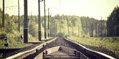 an empty train track with trees in the background