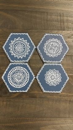 four blue and white coasters sitting on top of a wooden table