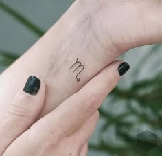 two hands holding each other with small tattoos on their thumbnails and one has the letter m in it