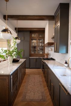 a long narrow kitchen with wooden cabinets and marble counter tops, along with an area rug on the floor