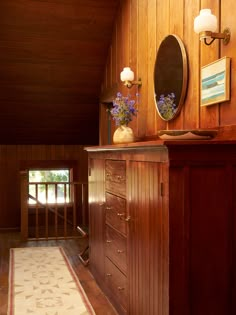 a room with wood paneling and flowers on top of the dresser next to it