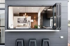 three stools sit in front of a window with a view of the kitchen and living room