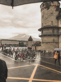 people with umbrellas are standing outside in the rain near some buildings and bicycles parked on the street