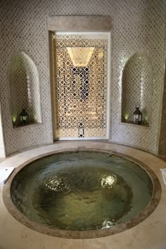 an indoor jacuzzi tub in the middle of a room with decorative tiles on the walls