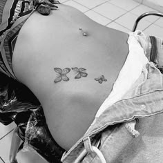 a woman's stomach with three butterflies tattoo on her belly and the bottom part of her lower back