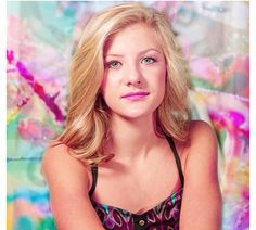 a woman is posing for a photo in front of a colorful background