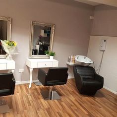 a hair salon with chairs, mirrors and flowers on the table in front of it