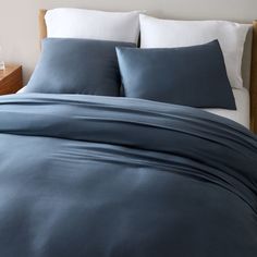 a bed with blue sheets and white pillows