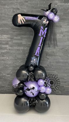 the number one balloon sculpture is decorated with black, purple and silver balloons that spell it's 1