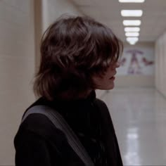 a woman standing in a hallway with her back to the camera and looking at something