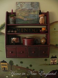 a shelf with pictures and other items on it in front of a painted wall mural