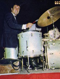 a man in a suit playing drums on stage