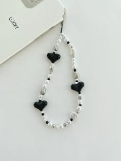 a white and black beaded necklace next to a camera