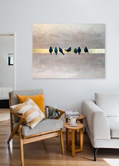 three birds sitting on a branch in the middle of a living room with white walls