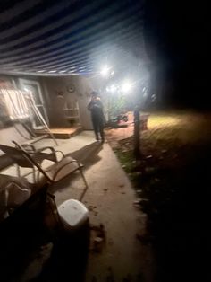 a man standing next to a pile of chairs under a roof with lights on it