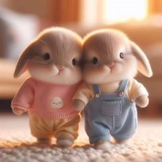 two small rabbits are standing next to each other on the floor, one is wearing overalls