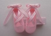 two pairs of pink baby shoes with bows on the top and one pair tied up