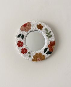 a decorative mirror with flowers painted on the front and sides, hanging from a wall