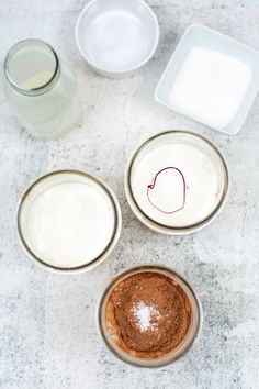 four bowls with different types of food in them on a counter top next to milk and yogurt