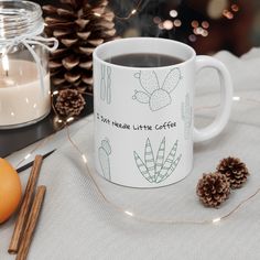 a cup of coffee sitting on top of a table next to an orange and some cinnamons