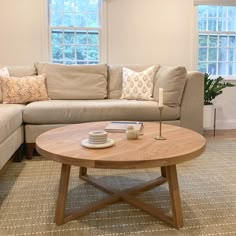 a living room with a couch, coffee table and two windows in it's corner