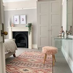 a bedroom with a fireplace, mirror and rug