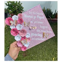 someone is holding up a pink and white graduation cap with paper flowers on the front