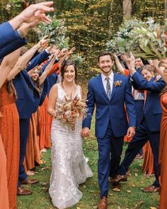 a bride and groom are walking through the grass with their hands in the air as they leave