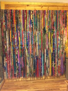 an art piece made out of colorful ribbons on display in a room with wood flooring