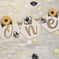 two bees and sunflowers are hanging from a string with the word love spelled on it