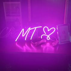 a neon sign that says mtt on it next to a laptop and headphones