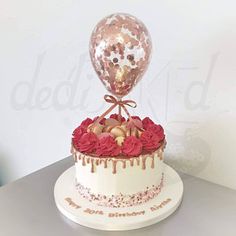 a birthday cake decorated with flowers and a balloon