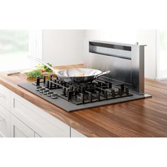 a frying pan sitting on top of a wooden counter next to a stovetop