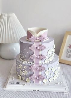 a three tiered cake with flowers and pearls on it