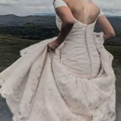 a woman in a white wedding dress walking down a hill with her back to the camera