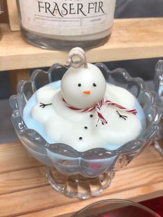 a candle in a glass bowl with a snowman decoration on the front and side