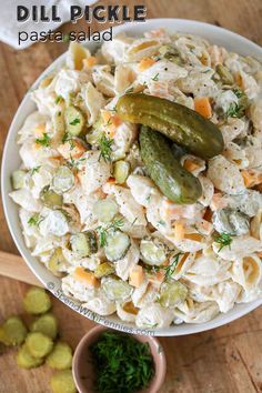 a bowl filled with pasta salad and a pickle sitting on top of the side