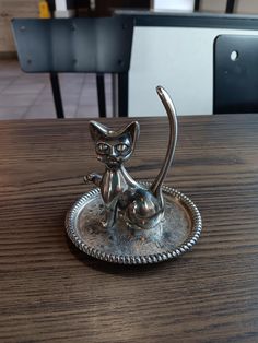 a silver cat figurine sitting on top of a wooden table