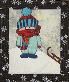 a quilted wall hanging with an image of a snowman holding a sled