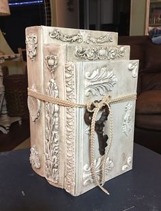 an old book is wrapped in rope and decorated with flowers, leaves and vines on a table