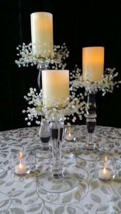 four candles are sitting on a table with white flowers