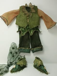 an old fashion doll with green clothes and netting on the bottom, sitting next to other items