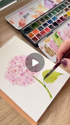 someone is painting flowers with watercolors on paper