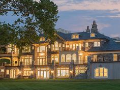 a large house with lots of windows and lights on it's front lawn at night