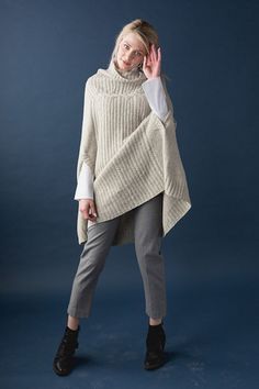 a woman is posing for the camera wearing a sweater and pants with an open neck